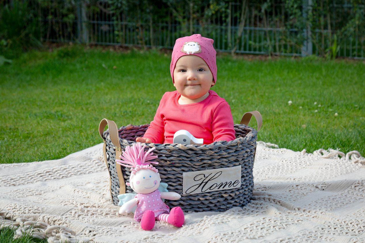 Kleinkind in einem Flechtkorb sitzend