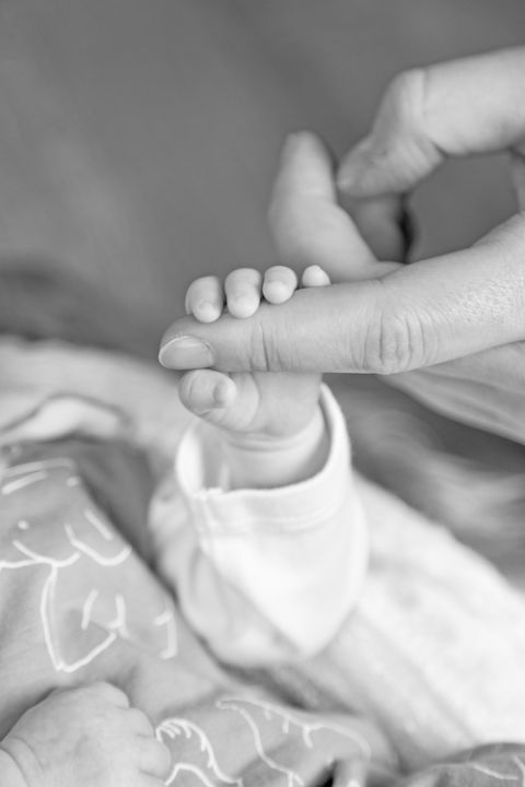 Baby, dass den Finger seiner Mutter hält