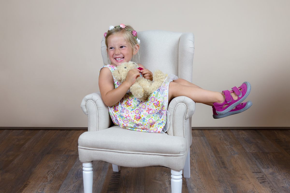 Junges Mädchen mit Kuscheltier in einem Sessel