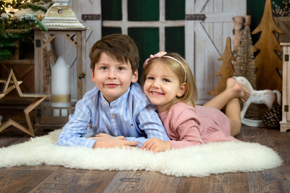 Zwei Kleinkinder auf dem Boden liegend vor weihnachtlicher Dekoration
